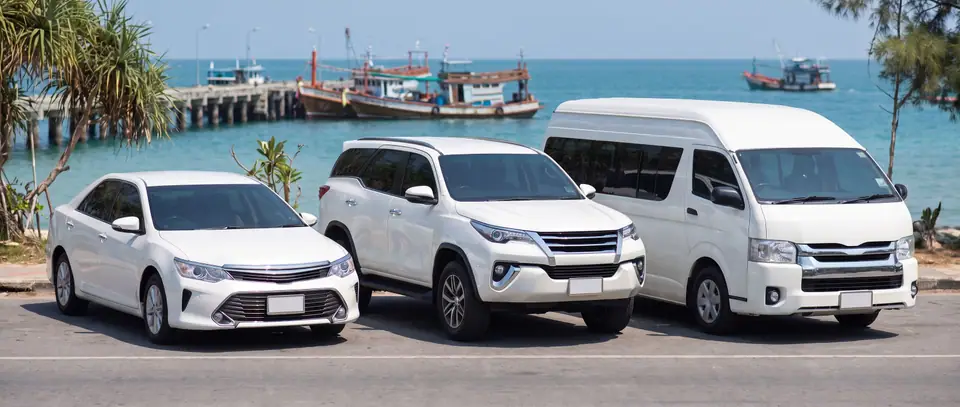 Sedan, SUV and van taxis parked on a seaside road near Ban Phe pier
